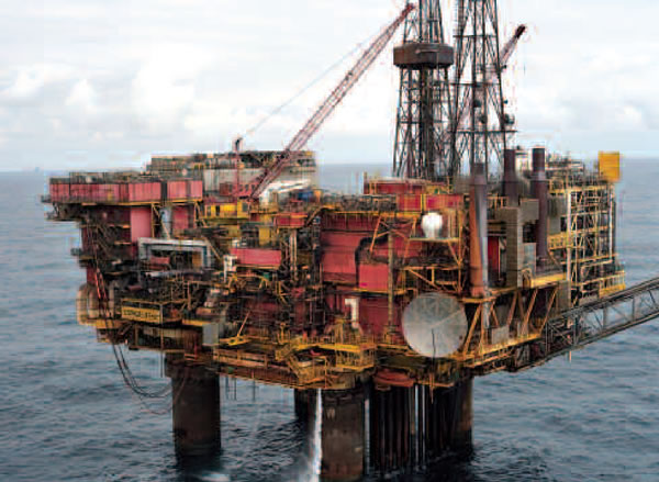 An offshore oil platform with a crane on top in the middle of the ocean