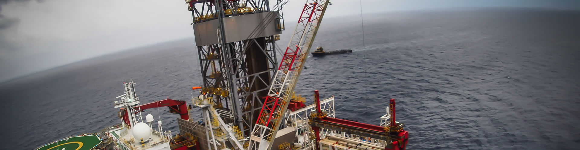 Oil rig in the ocean surrounded by waves, under a cloudy sky.